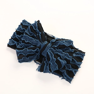 Détail du bandeau bébé avec nœud rayé noir et bords à volants bleu vif sur maille