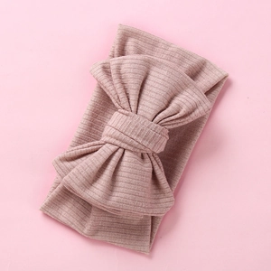 Detail of soft ribbed knit baby headband with oversized bow in dusty rose color