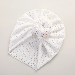 Detail view of white eyelet lace baby turban hat with decorative top donut knot