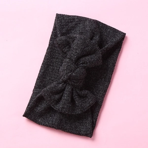 Detail of soft ribbed knit texture on a wide elastic baby headband with large bow tie
