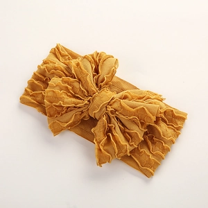 Détail d'un bandeau jaune pour bébé avec grand nœud à volants et tissu texturé doux