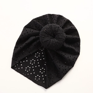Detail of black eyelet lace baby turban hat with a top knot donut on white background