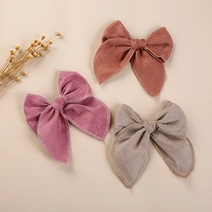 Détail de trois barrettes nœuds en lin brodé avec texture de tissu et surpiqûres