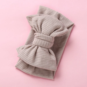 Detail of baby headband with oversized double-layered bow in soft ribbed knit fabric