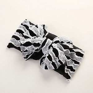 Détail d'un bandeau bébé en tissu noir avec nœud papillon en dentelle blanche à volants
