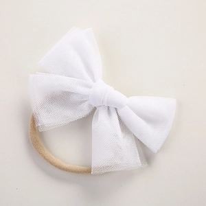 Detailed view of white mesh bow on a soft nude nylon headband for infants and newborns