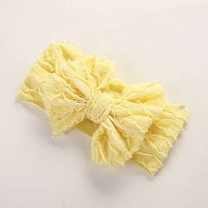 Détail du bandeau bébé en maille côtelée jaune avec un grand nœud papillon texturé