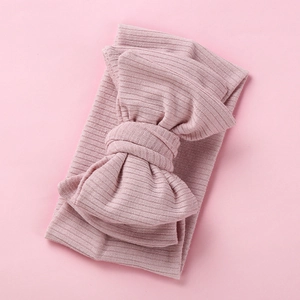 Detail of soft ribbed knit baby headband with oversized bow in dusty pink color