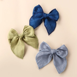 Détails des barrettes nœuds en lin avec bordure brodée en bleu, vert et gris clair