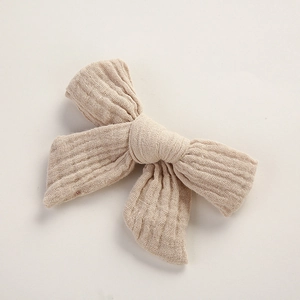 Vue détaillée de la texture du tissu en mousseline sur une pince à cheveux crème pour bébé