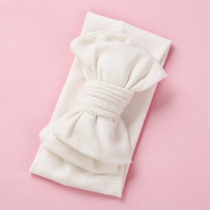 Detail of soft ribbed white baby headband featuring a large oversized knit bow