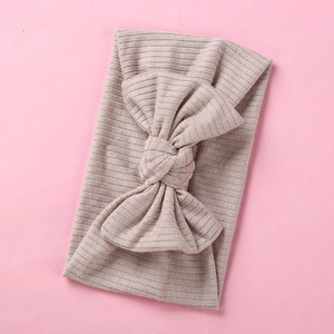 Close-up of beige ribbed knit baby headband featuring a soft elastic bow design