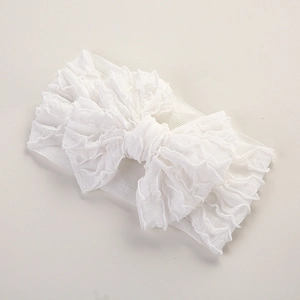 Détail d'un bandeau blanc pour bébé montrant le double nœud et la texture plissée