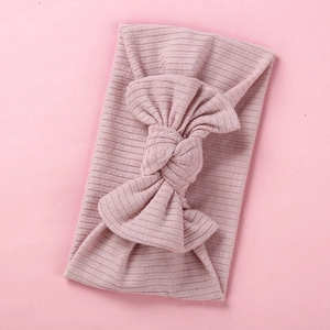 Detailed close-up of pink ribbed knit baby headband featuring a large knotted bow design