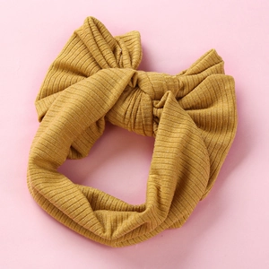 Close-up of mustard yellow ribbed knit baby headband with a large decorative bow