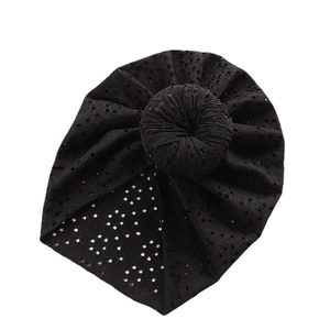 Black eyelet lace baby turban hat with donut knot decoration on white background