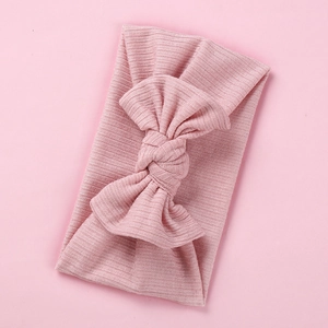 Close-up of soft pink ribbed knit baby headband with a large elastic decorative bow