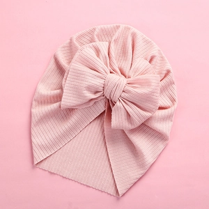 Detail of soft ribbed knit baby turban with oversized bow in solid pastel pink color
