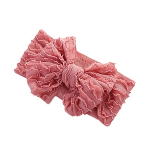 Bandeau élastique rose pour bébé avec un grand nœud à volants sur fond blanc