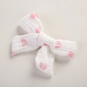 Détail d'un nœud à cheveux en mousseline blanche avec cœurs roses et texture gaufrée