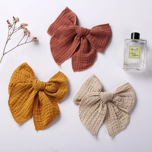 Set of three muslin bow hair clips in rust red, mustard yellow, and beige for girls
