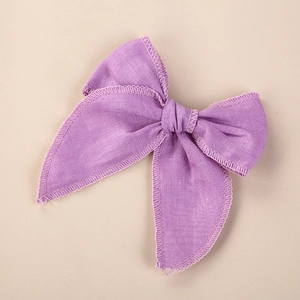Détail de la pince à cheveux noeud en lin violet montrant la bordure brodée de qualité