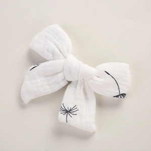 Détail du nœud de cheveux en mousseline blanche avec motifs de pissenlits noirs et coton
