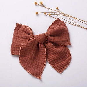 Macro detail of rust red muslin fabric texture and stitched edges on a bow hair clip