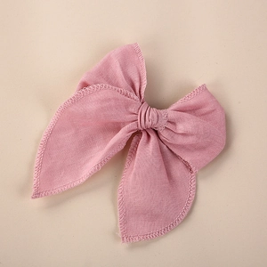 Gros plan d'un nœud papillon en lin rose avec bord brodé et texture de tissu fin