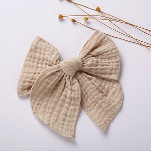 Close-up of beige muslin double-layer bow hair clip with textured crepe fabric details