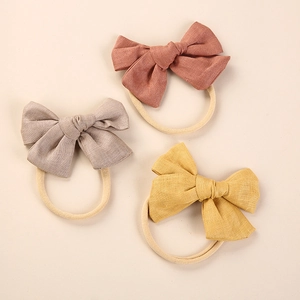 Three-piece linen bow headbands in soft pink, grey-purple and yellow on elastic nylon band