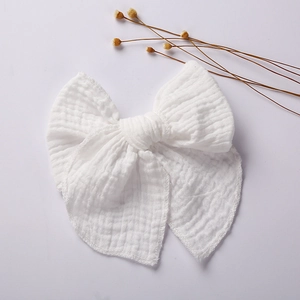 Detail of a white muslin cotton bow hair clip for girls with natural soft fabric texture