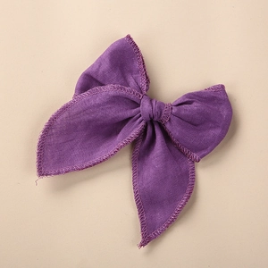 Détail de la pince à cheveux nœud en lin violet avec broderie fine sur fond crème clair