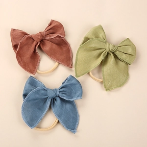 Detailed set of three linen bow headbands in brick red, olive green, and denim blue colors
