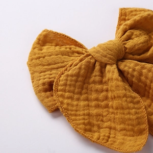 Detailed close-up of ginger yellow muslin cotton gauze bow with fine stitched edges