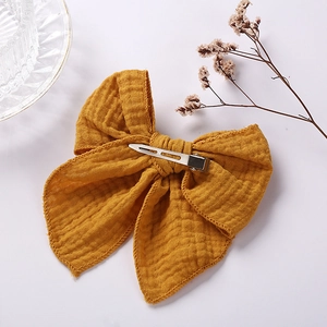 Detailed macro view of mustard yellow muslin cotton hair bow with metal duckbill clip back