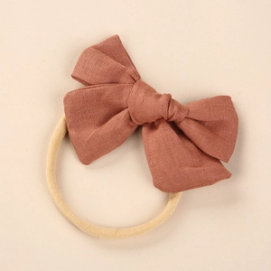 Detail of baby linen bow headband showing soft nylon elastic and breathable fabric texture