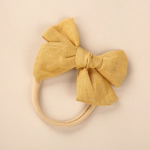 Detailed macro of mustard yellow linen bow with soft seamless elastic nylon baby headband