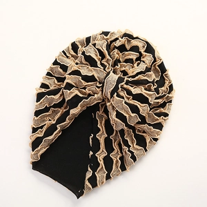 Detailansicht eines Baby-Turbans aus schwarzem Faltenstoff mit goldener Spitzenrüsche