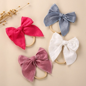 Detail of four linen bow headbands in rose, blue, pink and beige for baby girls