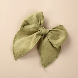 Détail d'un nœud à cheveux en lin vert herbe avec bordure brodée de style vintage