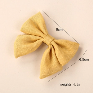 Handmade linen bow hair clip in ginger yellow, 8cm wide with natural textile texture