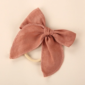 Detailed close-up of linen bow headband with fine overlock stitching and elastic nylon band