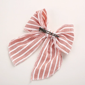 Détail d'un nœud papillon à rayures rouges et blanches avec de longs glands et clip métal