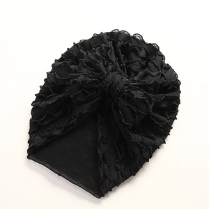 Detail eines schwarzen Baby-Turbans mit mehrlagigen Falten und feiner Spitzenverzierung