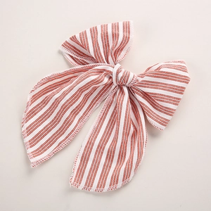 Détail de la pince à cheveux noeud rayé rouge et crème en tissu texturé de haute qualité