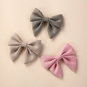 Detailed texture of handmade linen hair bows in grey, beige and pink for girls
