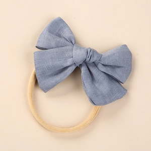 Close-up of blue-grey linen bow on a soft nylon headband for newborn babies