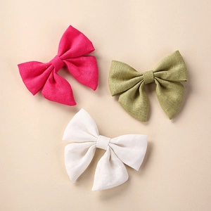 Detailed texture of pure linen handmade hair bows in rose red, green and white colors