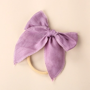 Detailed macro shot of purple linen bow hairband with precise embroidered edge stitching
